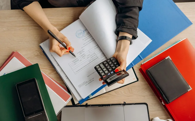 Analiza dokumentów finansowych z kalkulatorem przy biurku.